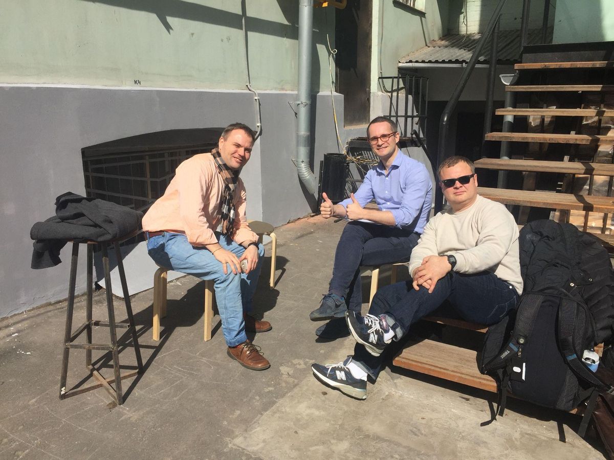 Three men on a sunny courtyard step