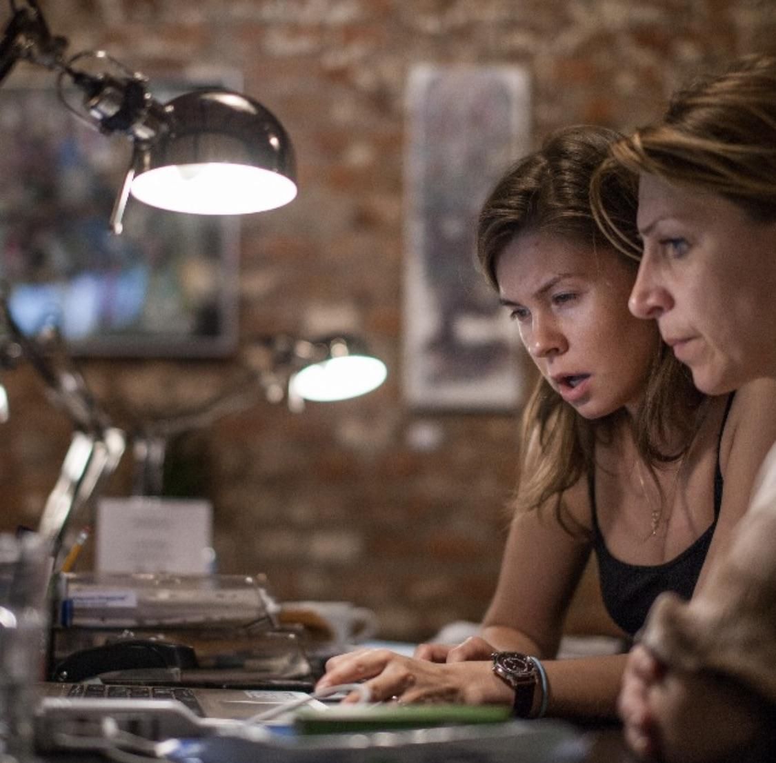 Two women working at a desk under a lamp