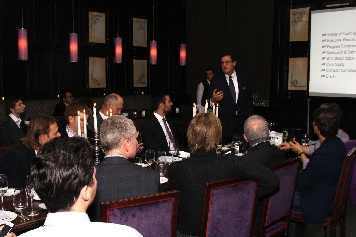 A dinner talk by candlelight, the speaker standing at the head of a long table