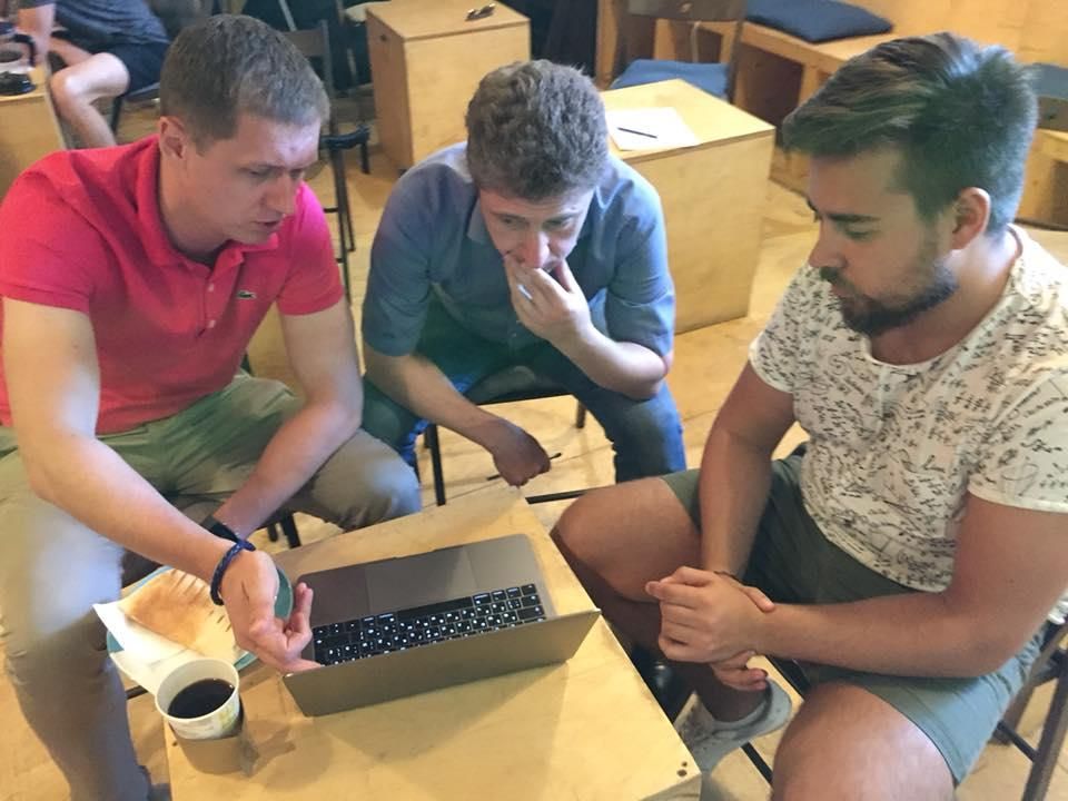 Three men leaning over one laptop